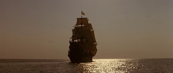 Movie still from “Pirates” (1986), directed by Roman Polanski – A large sail boat sailing on the water; Extreme Wide shot, Low angle