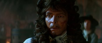 Movie still from “Pirates” (1986), directed by Roman Polanski – A person wearing a wig; Close Up shot, Over the shoulder angle