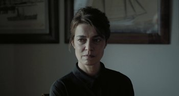 Movie still from “Pity” (2018), directed by Babis Makridis – A person wearing a black shirt; Close Up shot, Over the shoulder angle