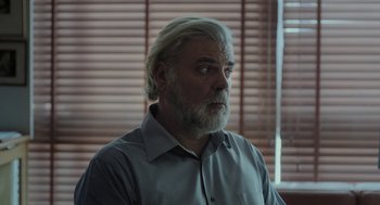 Movie still from “Pity” (2018), directed by Babis Makridis – A man with a gray beard is looking into the distance; Close Up shot, Low angle