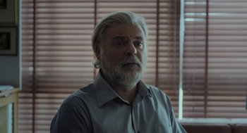 Movie still from “Pity” (2018), directed by Babis Makridis – An older man with a beard is looking at the camera; Close Up shot, Low angle