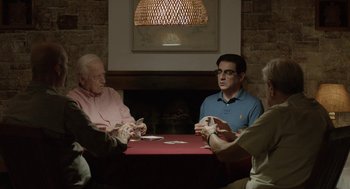 Movie still from “Pity” (2018), directed by Babis Makridis – A group of people sitting at a table playing cards; Medium shot, Over the shoulder angle