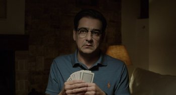 Movie still from “Pity” (2018), directed by Babis Makridis – A man holding a deck of playing cards in his hands; Medium shot, Over the shoulder angle