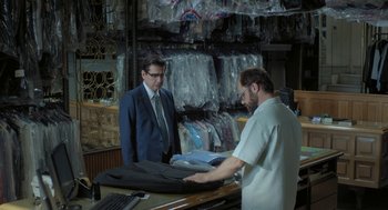 Movie still from “Pity” (2018), directed by Babis Makridis – A man in a suit and a man in a tie; Medium shot, Over the shoulder angle