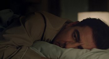 Movie still from “Pity” (2018), directed by Babis Makridis – A person laying in a bed with a pillow; Close Up shot, High angle