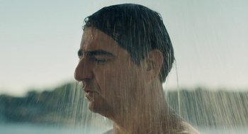Movie still from “Pity” (2018), directed by Babis Makridis – A person in the shower; Close Up shot, Over the shoulder angle