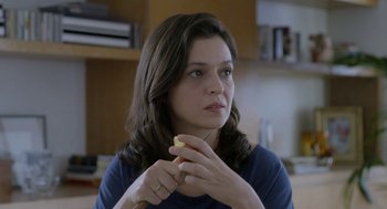 Movie still from “Pity” (2018), directed by Babis Makridis – A woman holding a piece of food in her hands; Close Up shot, Over the shoulder angle