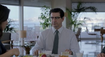 Movie still from “Pity” (2018), directed by Babis Makridis – A man sitting at a table with food in front of him; Medium shot, Over the shoulder angle