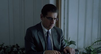 Movie still from “Pity” (2018), directed by Babis Makridis – A man in a suit and tie sitting in front of a computer; Close Up shot, Over the shoulder angle