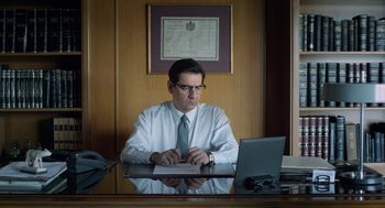 Movie still from “Pity” (2018), directed by Babis Makridis – A man sitting in front of a computer desk; Medium shot, Low angle