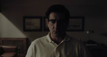 Movie still from “Pity” (2018), directed by Babis Makridis – A man in a white shirt is looking at the camera; Close Up shot, Low angle