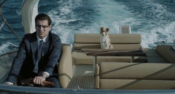 Movie still from “Pity” (2018), directed by Babis Makridis – A man and a dog sitting on a boat in the water; Medium shot, High angle
