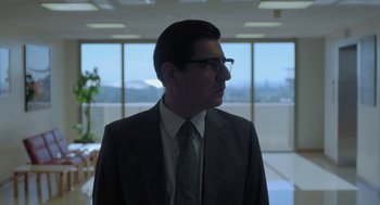 Movie still from “Pity” (2018), directed by Babis Makridis – A man in a suit and tie in an office setting; Medium shot, Low angle