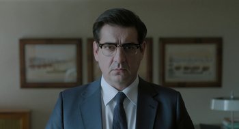 Movie still from “Pity” (2018), directed by Babis Makridis – A person wearing a suit and tie; Close Up shot, Low angle