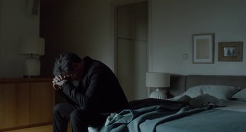 Movie still from “Pity” (2018), directed by Babis Makridis – A man sitting on a bed with his head on his hands; Medium shot, High angle