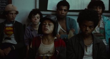 Movie still from “Pixote” (1980), directed by Hector Babenco – A group of young people sitting in a room; Medium shot, High angle