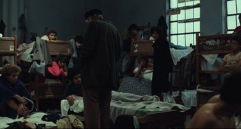 Movie still from “Pixote” (1980), directed by Hector Babenco – A group of people sitting in a room with beds; Wide shot, High angle