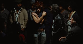 Movie still from “Pixote” (1980), directed by Hector Babenco – A group of people standing around each other in the dark; Medium shot, High angle