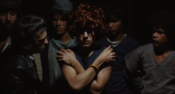 Movie still from “Pixote” (1980), directed by Hector Babenco – A group of young men standing next to each other in the dark; Medium shot, Over the shoulder angle