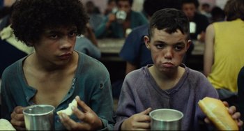 Movie still from “Pixote” (1980), directed by Hector Babenco – Two young men sitting at a table with a cup of coffee; Close Up shot, Low angle