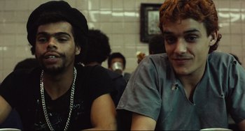 Movie still from “Pixote” (1980), directed by Hector Babenco – Two young men sitting next to each other in front of a brick wall; Close Up shot, Over the shoulder angle