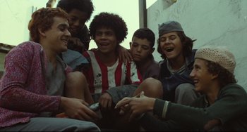 Movie still from “Pixote” (1980), directed by Hector Babenco – A group of young men sitting next to each other on the ground; Medium shot, Low angle