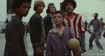 Movie still from “Pixote” (1980), directed by Hector Babenco – A group of young men standing next to each other holding a ball; Medium shot, Low angle
