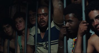Movie still from “Pixote” (1980), directed by Hector Babenco – A group of people behind bars in a room; Medium shot, High angle