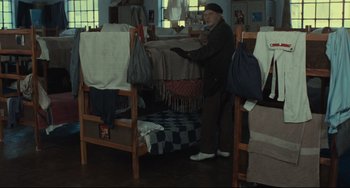 Movie still from “Pixote” (1980), directed by Hector Babenco – An old man standing in a room next to a bunk bed; Wide shot, High angle