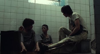 Movie still from “Pixote” (1980), directed by Hector Babenco – A group of young men sitting on the ground; Medium shot, Low angle