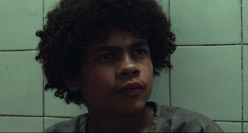 Movie still from “Pixote” (1980), directed by Hector Babenco – A young man with curly black hair looking at the camera; Close Up shot, Low angle