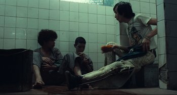 Movie still from “Pixote” (1980), directed by Hector Babenco – A group of people sitting on the floor eating food; Medium shot, Low angle