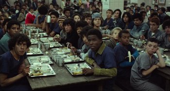 Movie still from “Pixote” (1980), directed by Hector Babenco – A group of people sitting at a table eating food; Wide shot, High angle