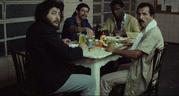 Movie still from “Pixote” (1980), directed by Hector Babenco – A group of people sitting at a table eating; Wide shot, High angle