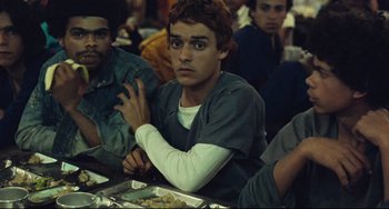 Movie still from “Pixote” (1980), directed by Hector Babenco – A group of young men sitting at a table; Medium shot, High angle