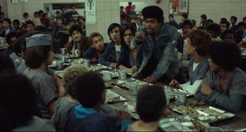 Movie still from “Pixote” (1980), directed by Hector Babenco – A group of people sitting at a table with food; Medium shot, Over the shoulder angle