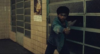 Movie still from “Pixote” (1980), directed by Hector Babenco – A man holding a gun in front of a brick wall; Medium shot, Low angle