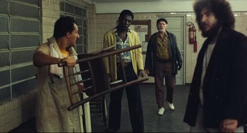 Movie still from “Pixote” (1980), directed by Hector Babenco – A group of men standing next to each other in a room; Wide shot, Over the shoulder angle