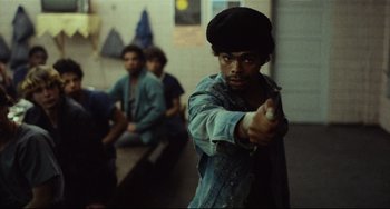 Movie still from “Pixote” (1980), directed by Hector Babenco – A young man holding a video game controller in his hand; Medium shot, Over the shoulder angle