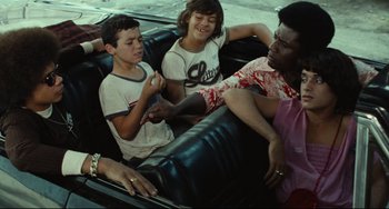 Movie still from “Pixote” (1980), directed by Hector Babenco – A group of young people sitting on a couch together; Medium shot, High angle