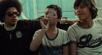 Movie still from “Pixote” (1980), directed by Hector Babenco – A young boy smoking a cigarette while sitting on a bus; Medium shot, Low angle