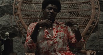 Movie still from “Pixote” (1980), directed by Hector Babenco – A man sitting in front of a metal fence; Medium shot, High angle