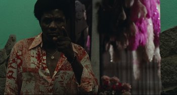 Movie still from “Pixote” (1980), directed by Hector Babenco – A man in a red and white shirt is pointing to his face; Medium shot, Low angle