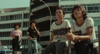 Movie still from “Pixote” (1980), directed by Hector Babenco – A group of young men sitting on top of a building; Medium shot, Low angle