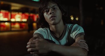 Movie still from “Pixote” (1980), directed by Hector Babenco – A young man sitting on top of a bench; Close Up shot, Low angle