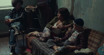 Movie still from “Pixote” (1980), directed by Hector Babenco – A woman sitting on a couch with two boys; Wide shot, High angle