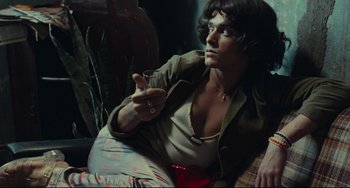 Movie still from “Pixote” (1980), directed by Hector Babenco – A man sitting on the ground holding a cell phone; Medium shot, Low angle