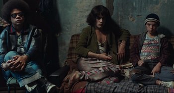 Movie still from “Pixote” (1980), directed by Hector Babenco – A woman sitting on a couch in a living room; Medium shot, High angle