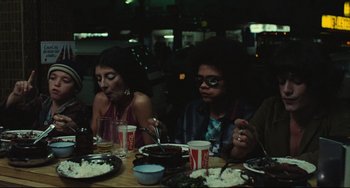 Movie still from “Pixote” (1980), directed by Hector Babenco – A group of people sitting at a table eating food; Medium shot, High angle