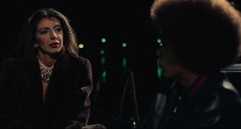 Movie still from “Pixote” (1980), directed by Hector Babenco – Two people are sitting in a dark room talking; Medium shot, Over the shoulder angle